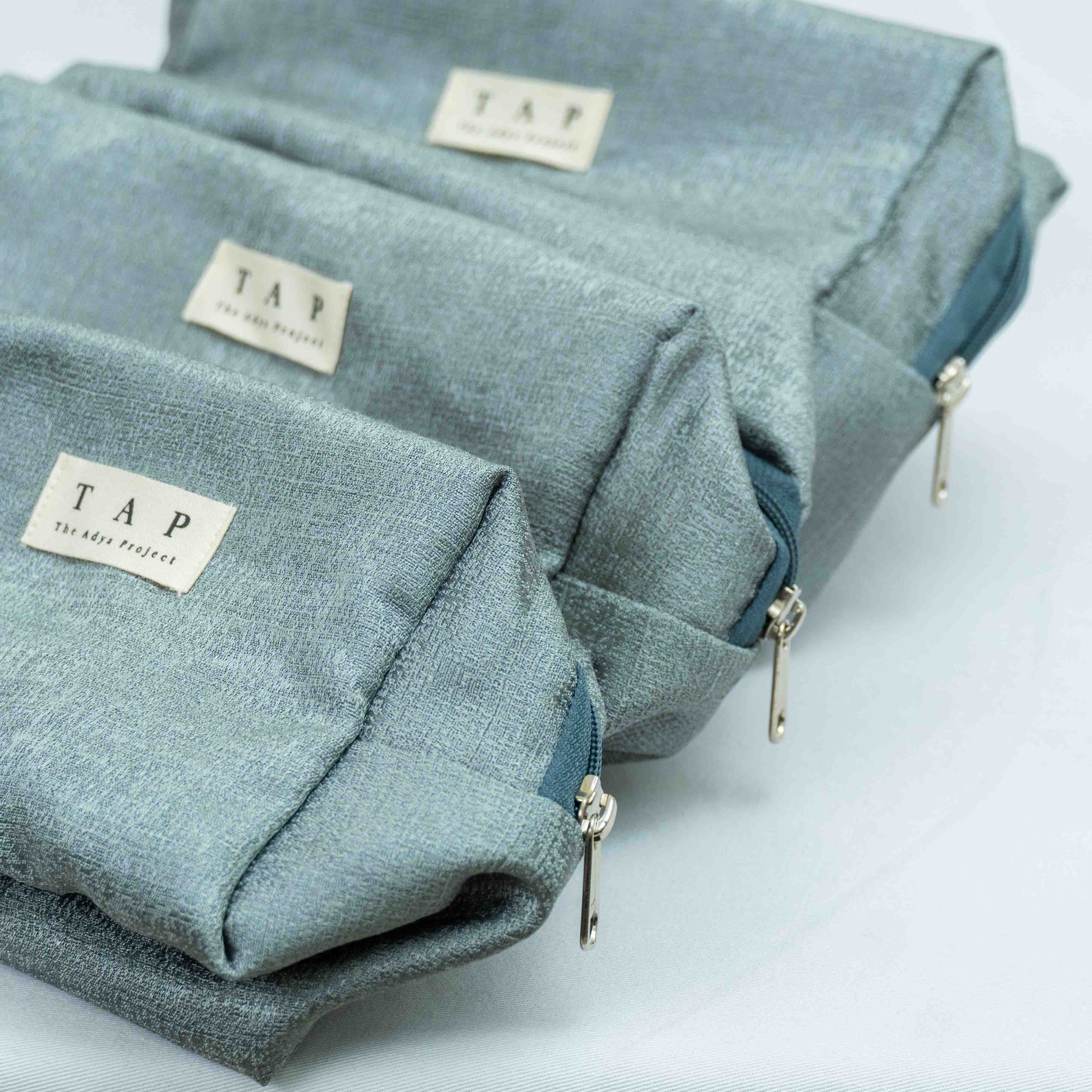 Two teal bags with 'TAP' labels on a light gray background