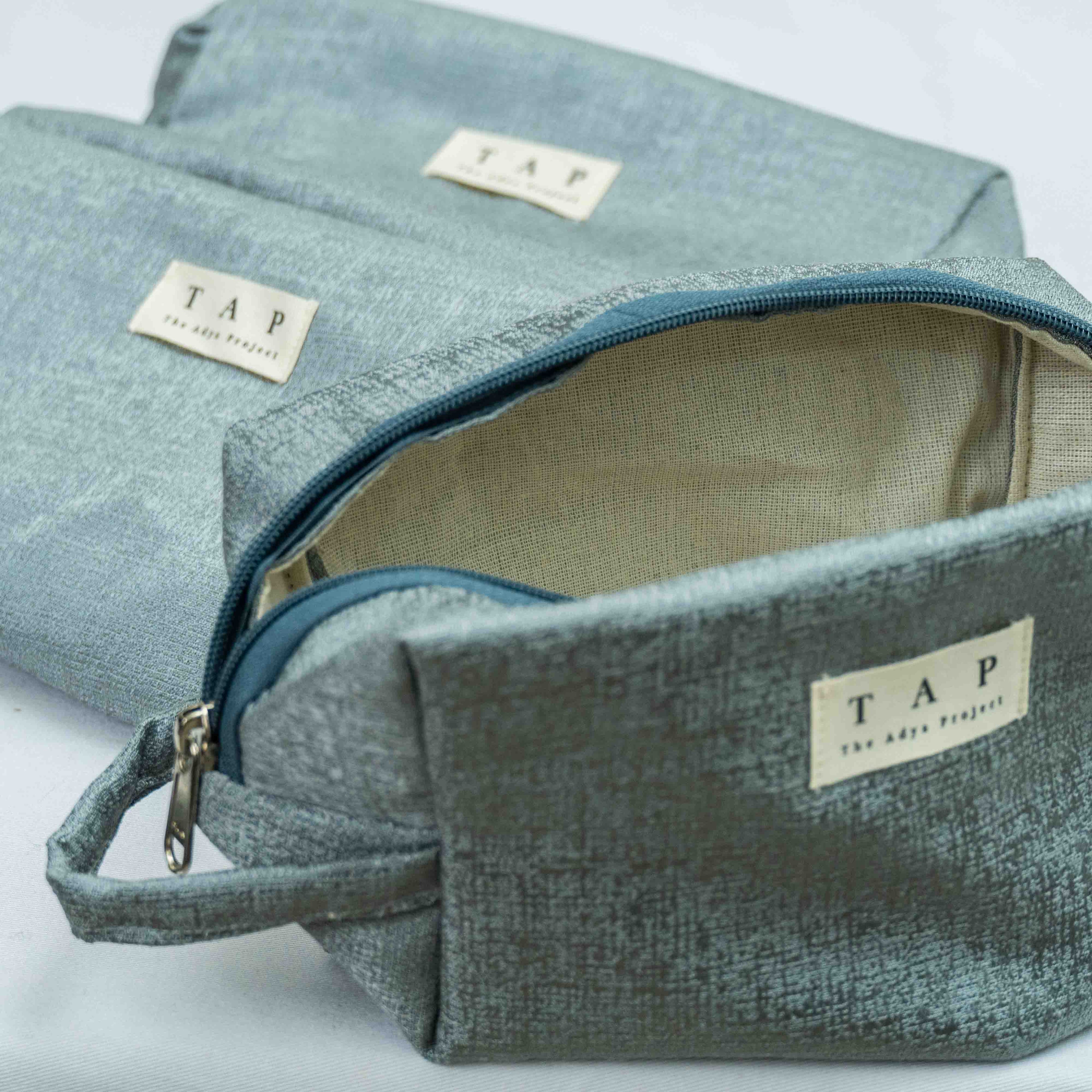 Blue textured toiletry bag with 'TAP' label on a light gray background