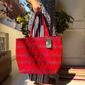 Person holding a red ikat-patterned bag with a tag indoors