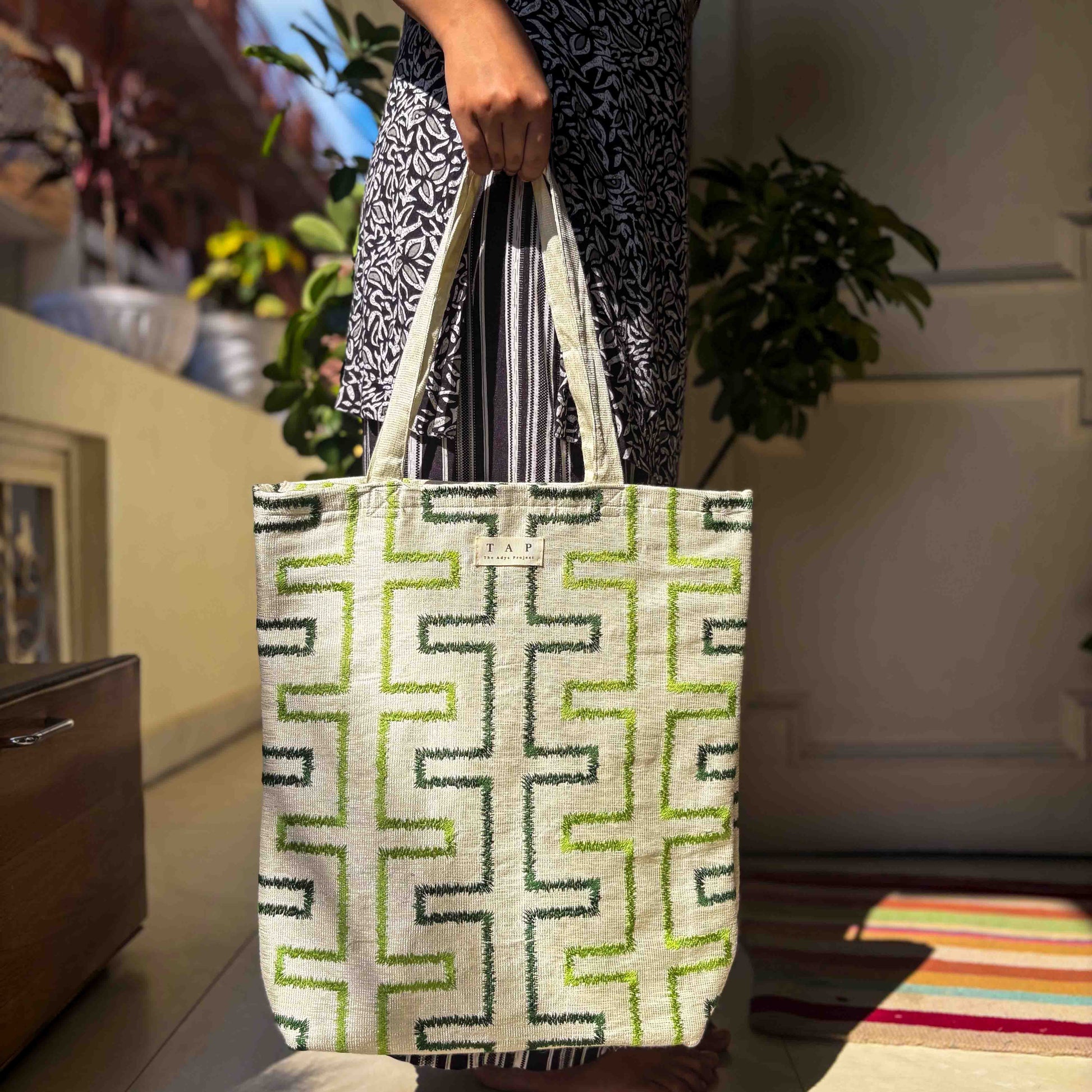 Person holding a tote bag with a geometric pattern in a home setting