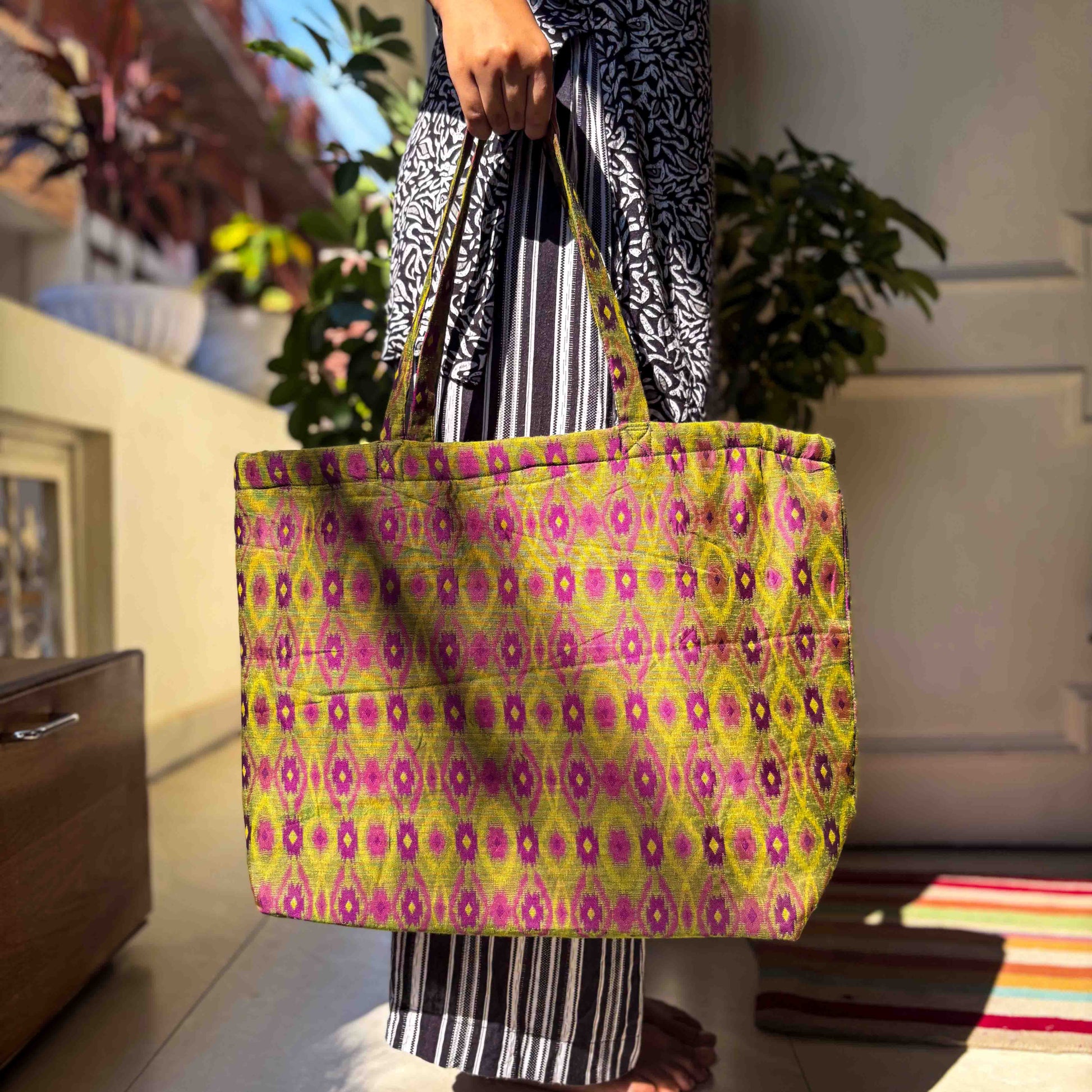 Person holding a colorful ikat patterned tote bag in an indoor setting