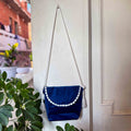 Blue bag with white details and tassels hanging on a door