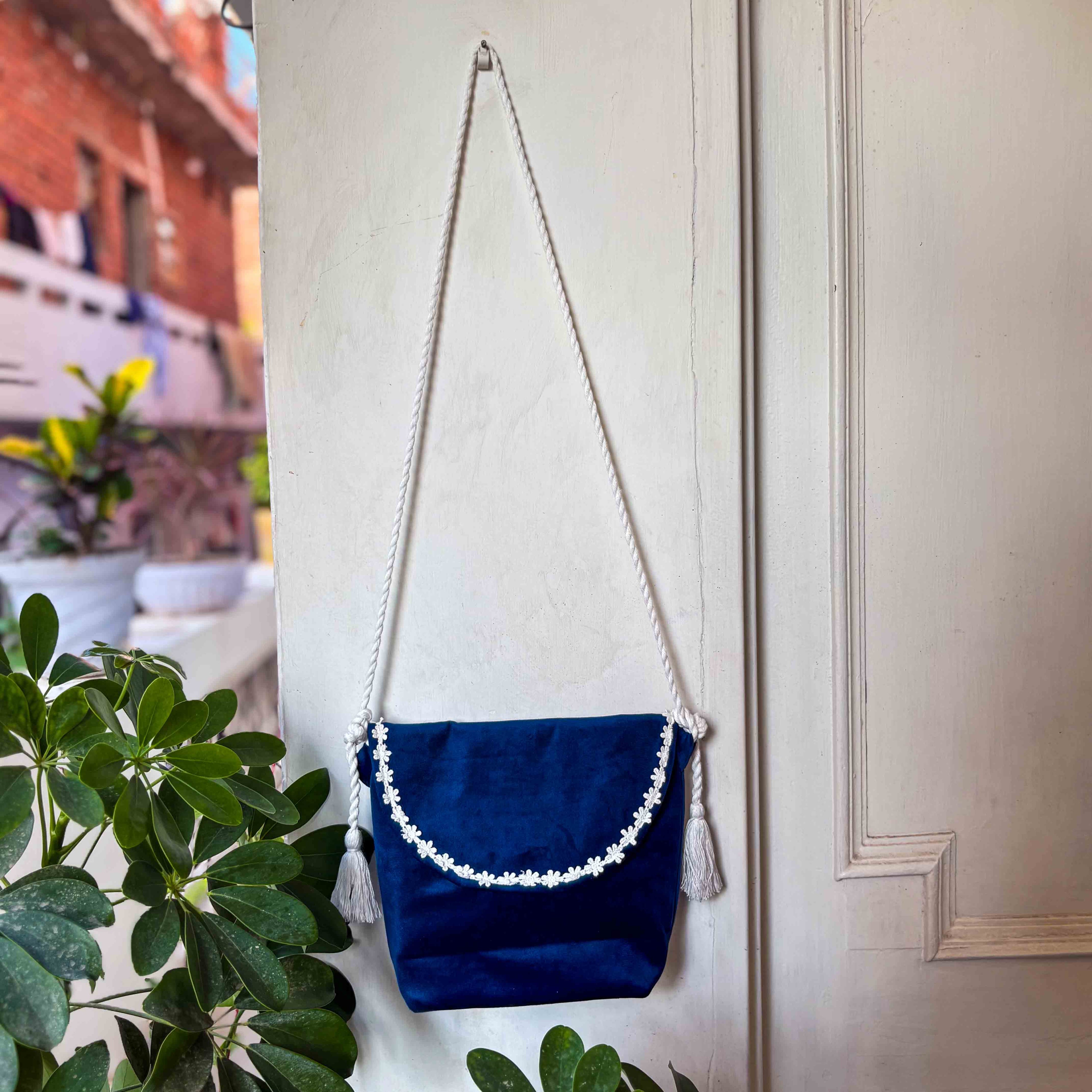 Blue bag with white details and tassels hanging on a door