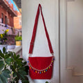 Red bag with colorful tassels hanging on a white door