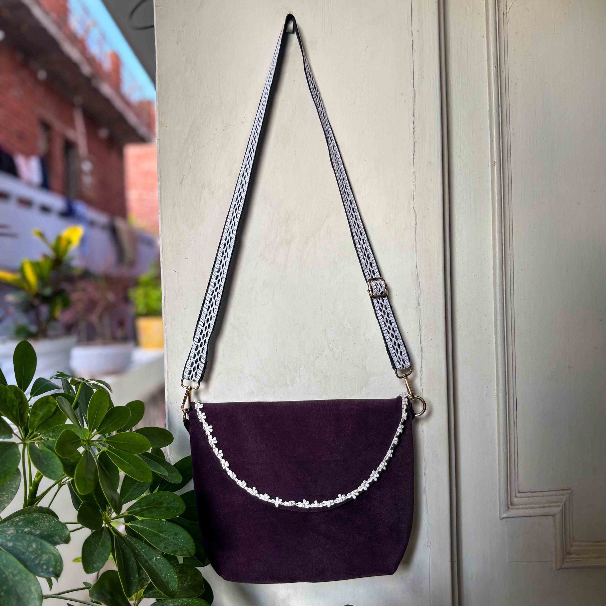 Purple handbag with a chain strap hanging on a door