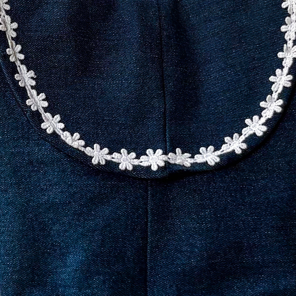 White floral Lace on a dark blue denim flap of the sling bag
