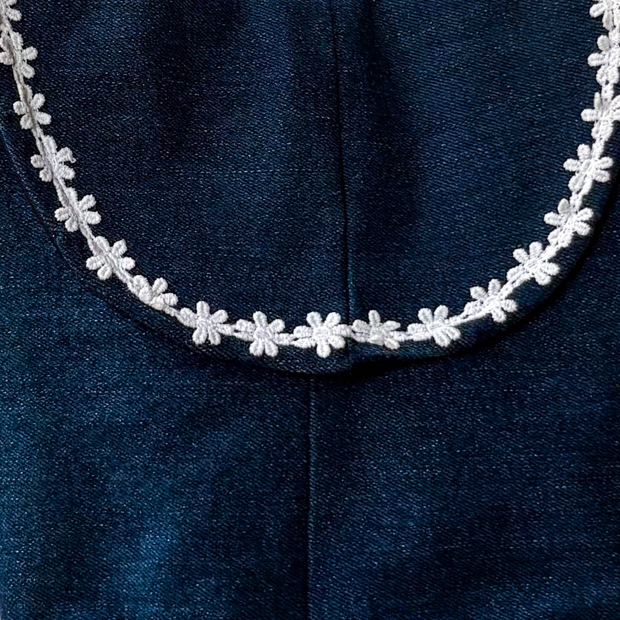 White floral Lace on a dark blue denim flap of the sling bag