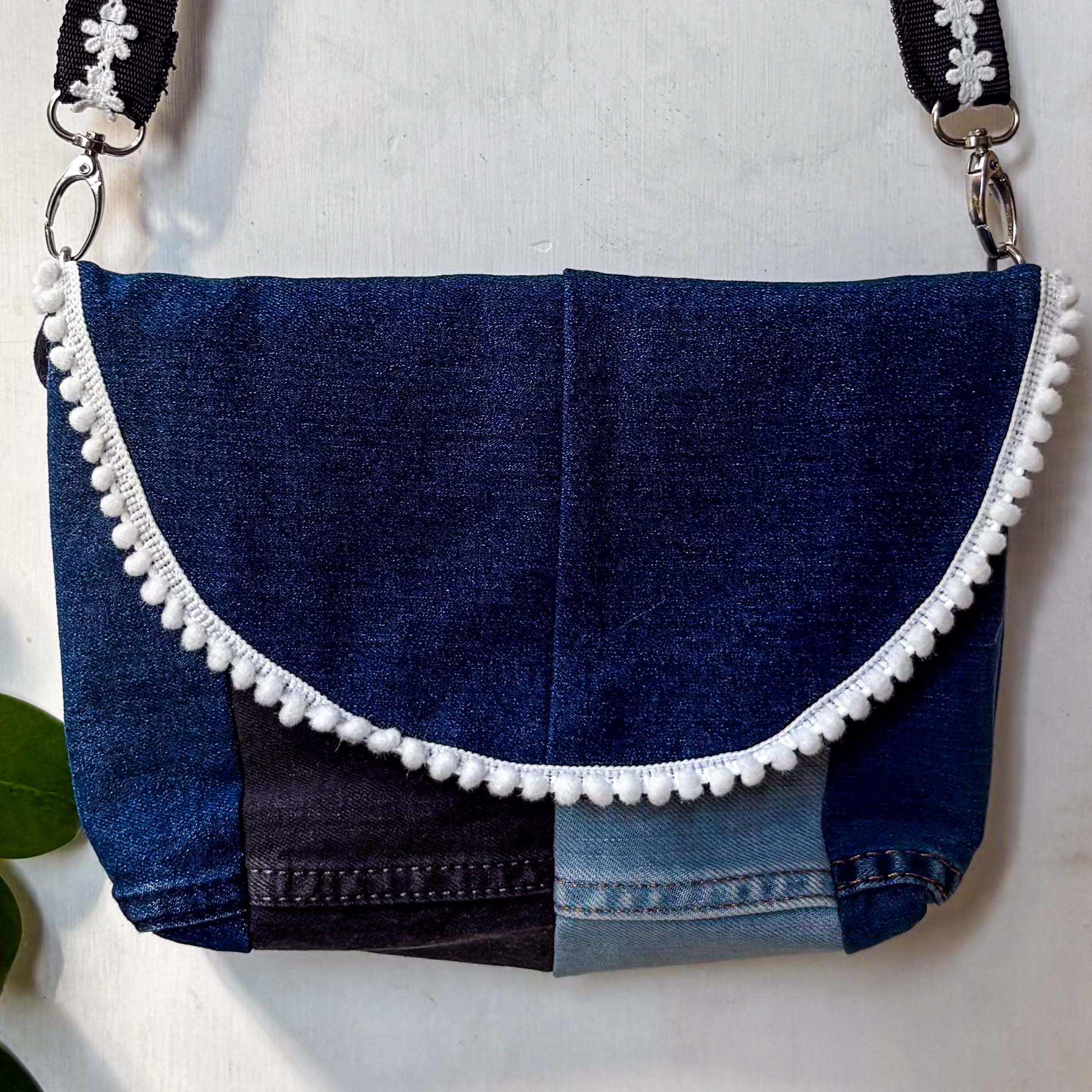 Blue denim handbag with white trim on a light background