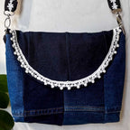 Blue denim handbag with decorative white trim on a white background