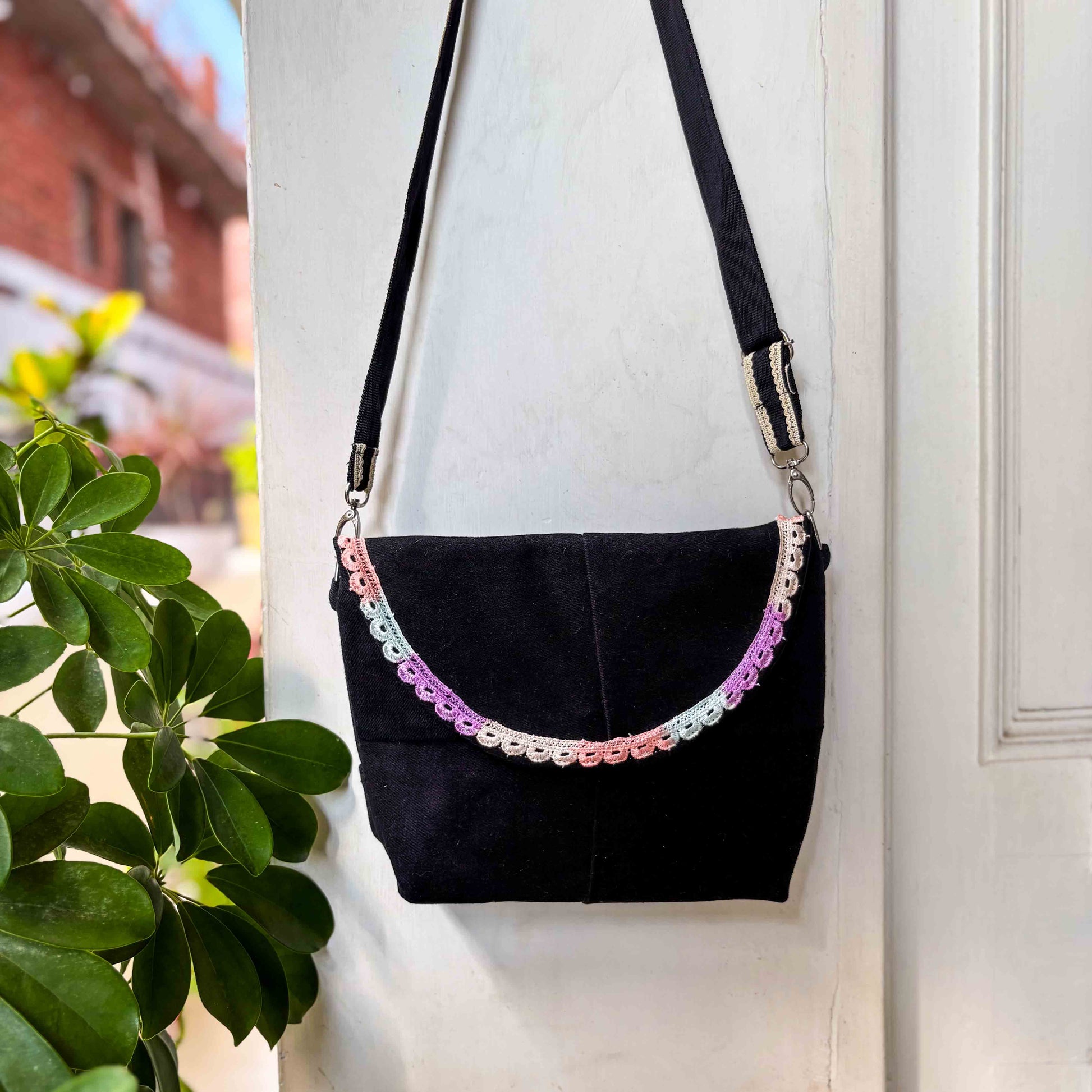 Black handbag with decorative chain strap against a white wall