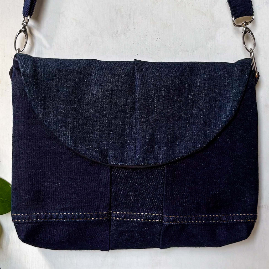 Navy blue denim bag with a strap on a white background