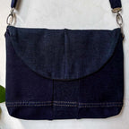 Navy blue denim bag with a strap on a white background