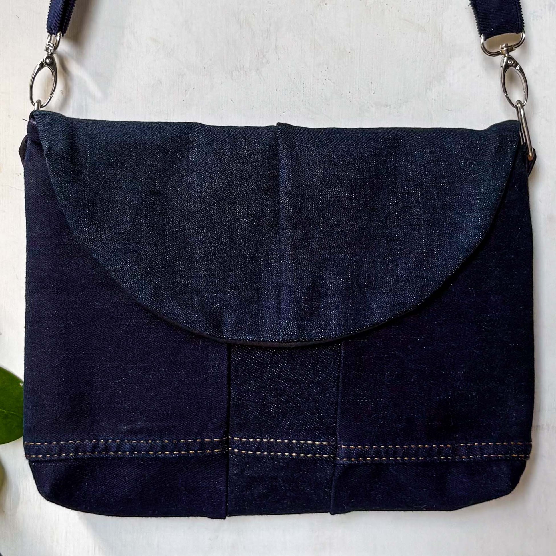 Navy blue denim bag with a strap on a white background