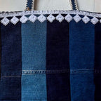 Blue denim bag with white lace trim on a wooden surface