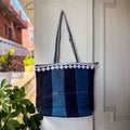 Blue striped tote bag with white trim hanging on a white door.