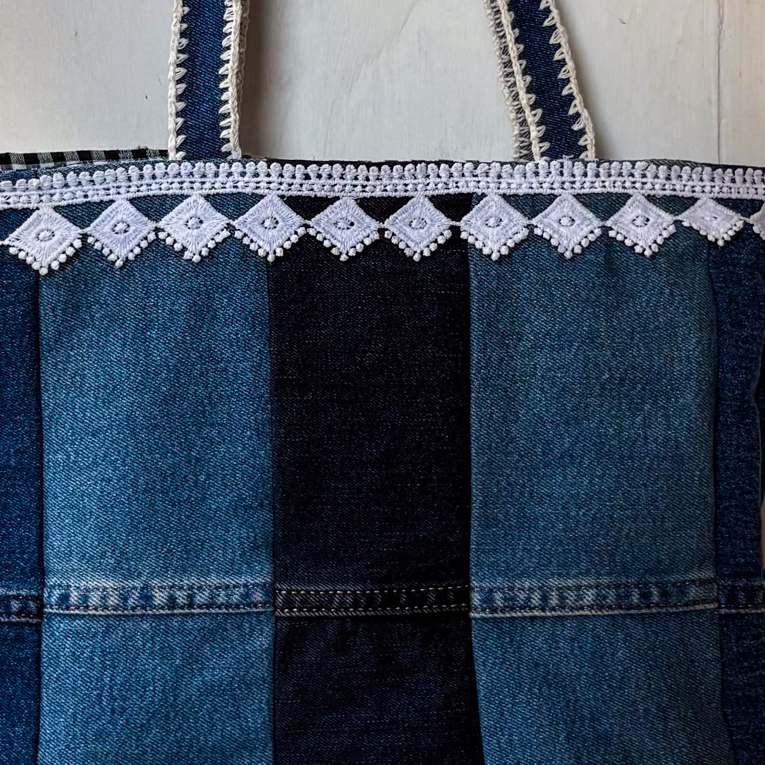 Denim apron with white lace trim on a white background