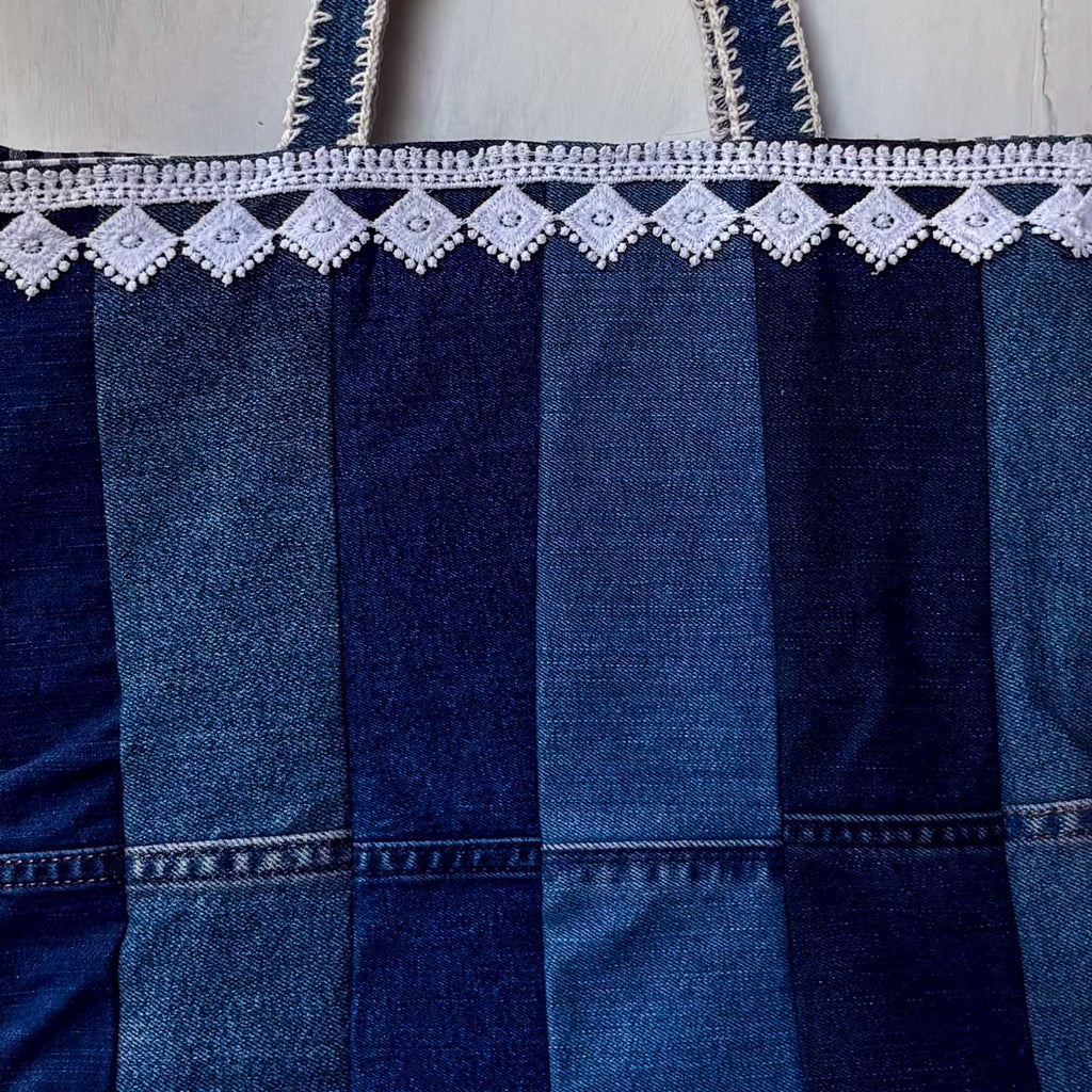 Blue denim bag with white lace detailing on a light wooden surface