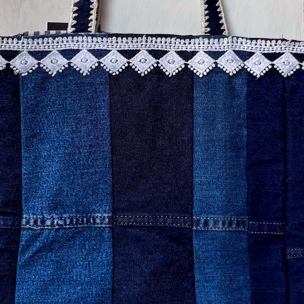Blue denim bag with white lace trim on a white background