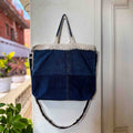 Blue denim bag with white crochet top hanging on a door